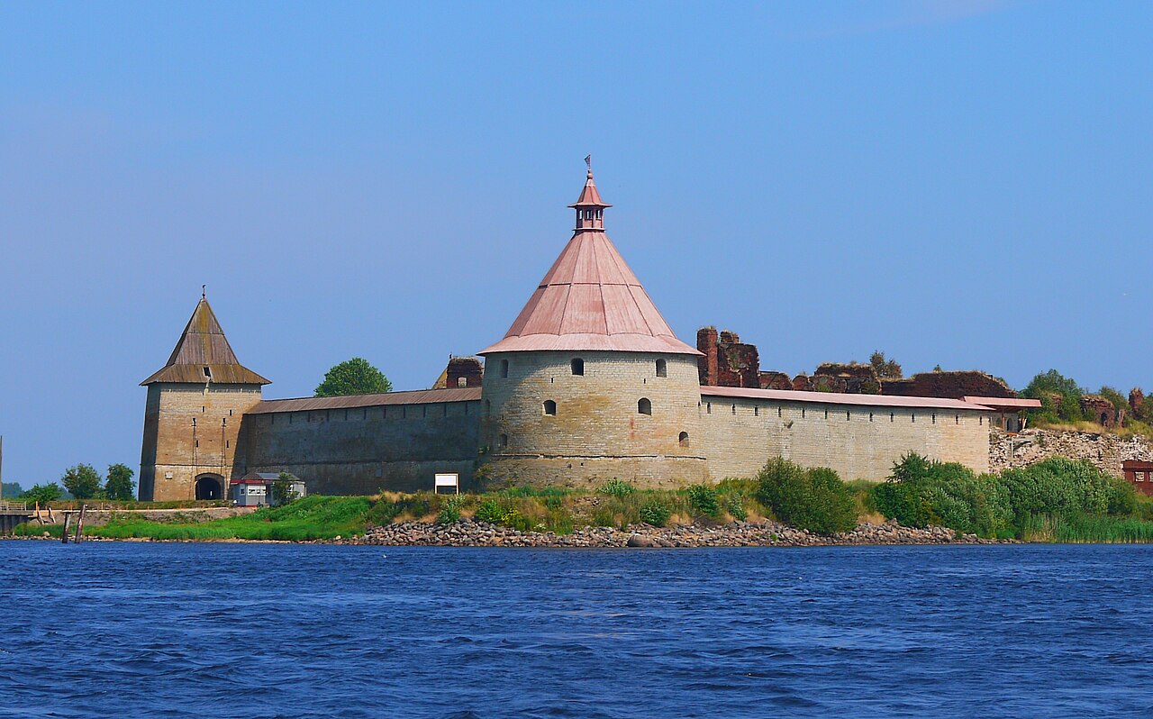 Каменная крепость с круглыми башнями на острове посреди широкой реки